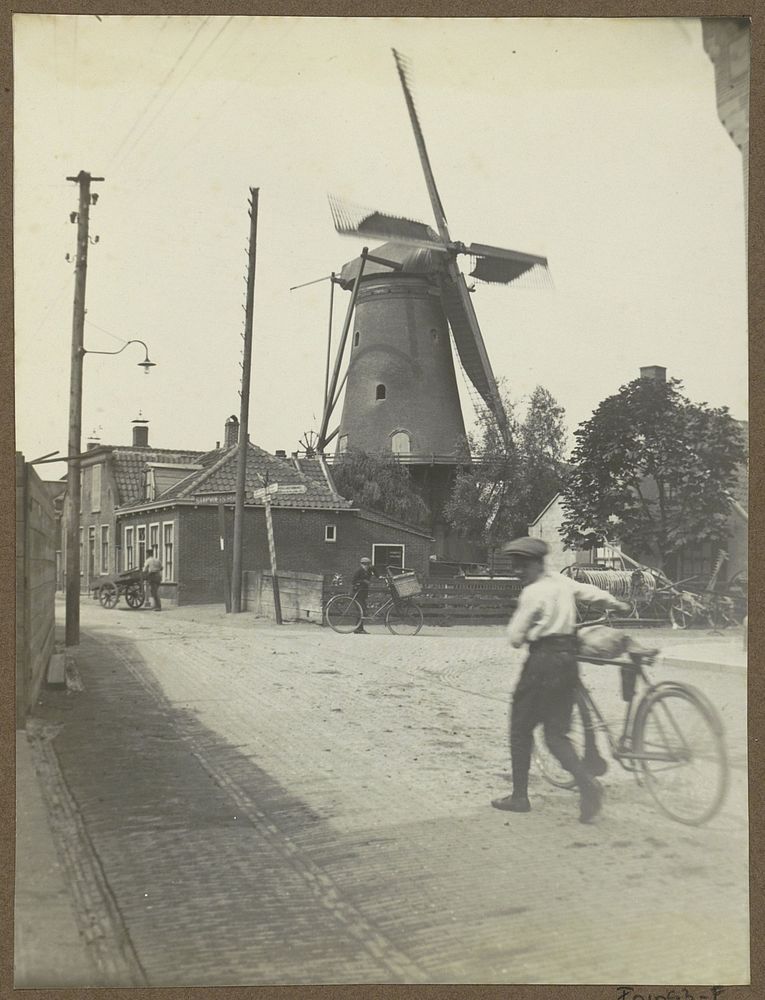 Jongens met fietsen en een handkar op de Amsteldijk in Uithoorn, ter hoogte van een molen (c. 1900 - c. 1915) by anonymous