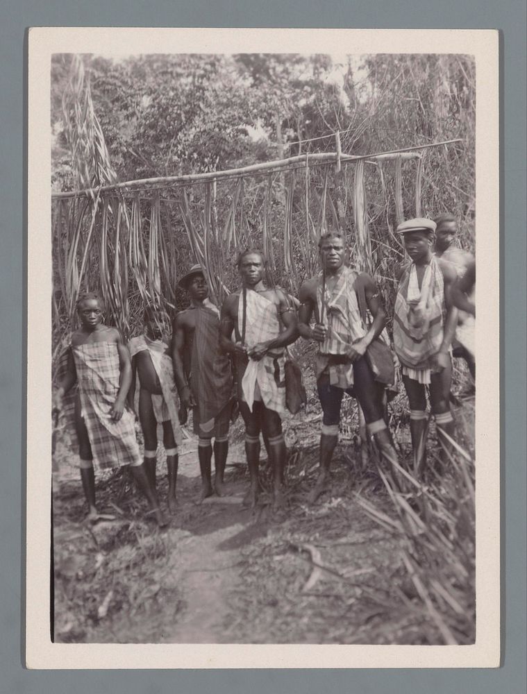 Zeven Marronmannen voor de ingang van een Marrondorp (vermoedelijk) te Suriname (c. 1910 - c. 1940) by anonymous