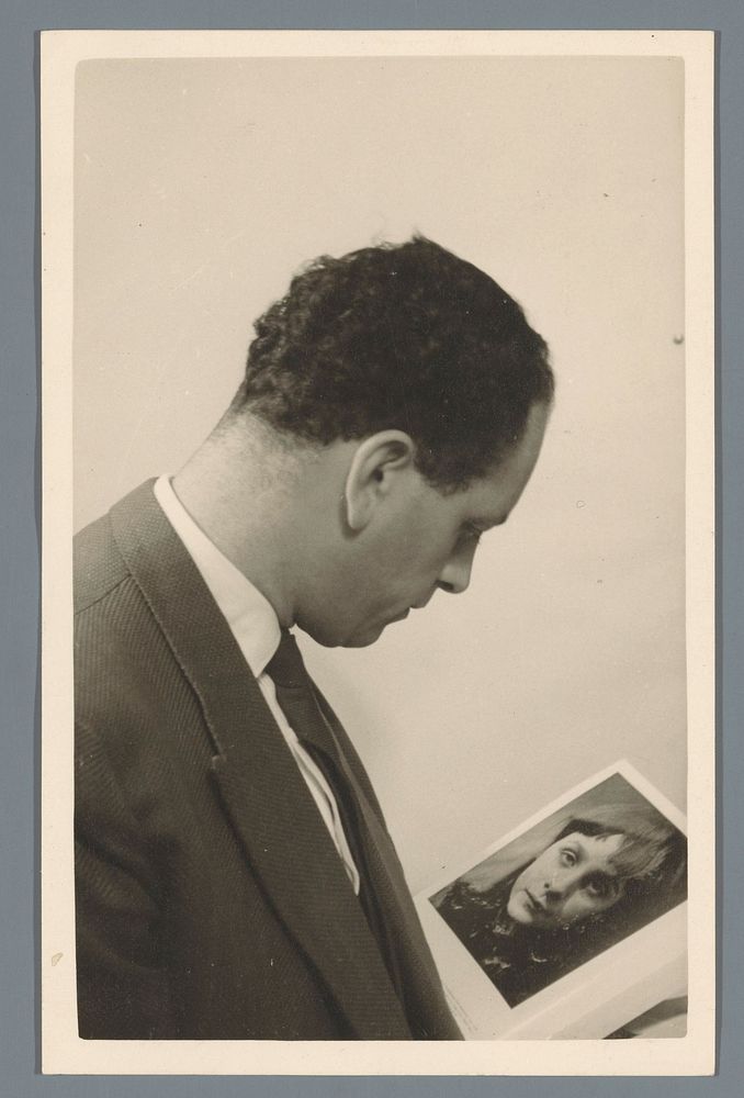 Onbekende man bekijkt een foto van een onbekende vrouw in een boek (c. 1930 - c. 1950) by anonymous