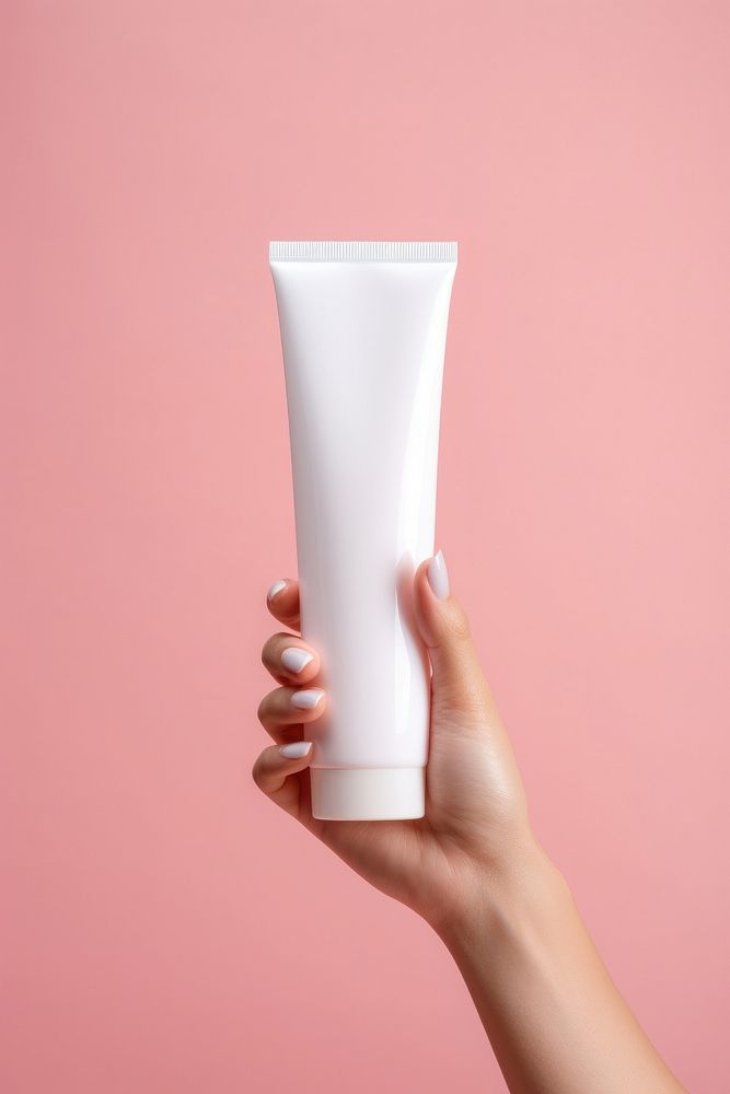 Hand holding squeeze bottle plastic tube container of cream milk refreshment cosmetics.