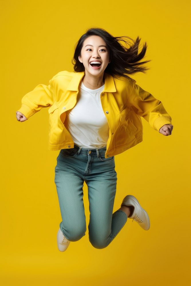 Young Chinese woman full-length jumping laughing smiling yellow.