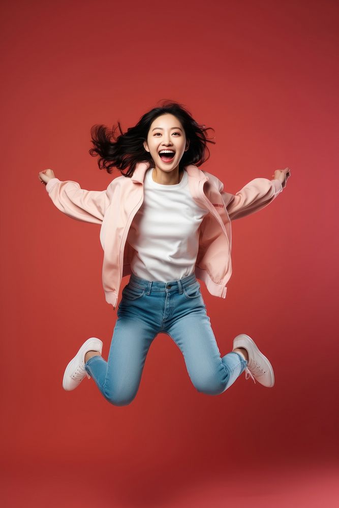Young Chinese woman full-length jumping shouting smiling fun.