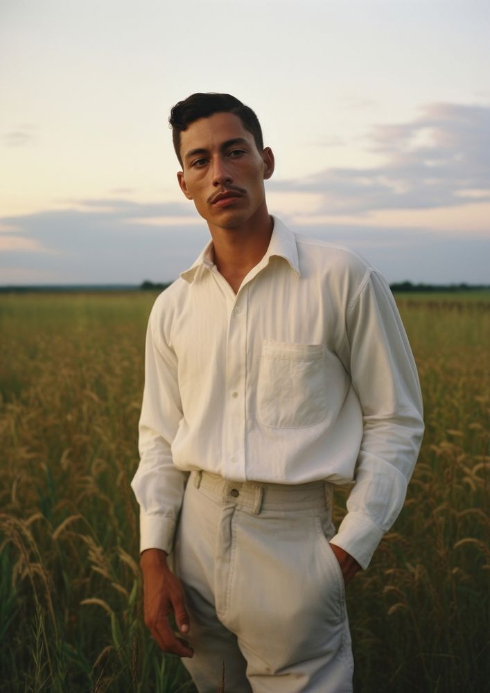 Hispanic man with minimal white shirt standing nature field.