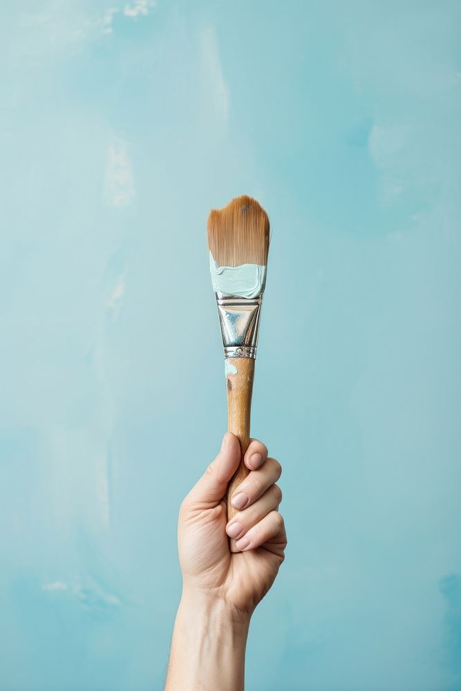Hand holds a paint brush tool paintbrush creativity.