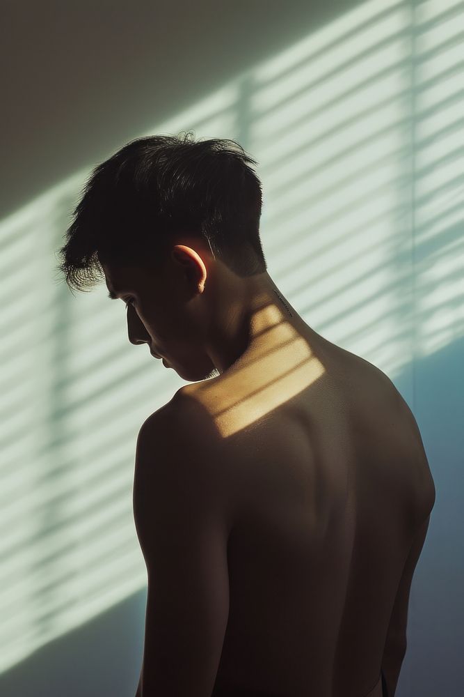 An east asian man suffering from back pain symptom contemplation barechested semi-dress.