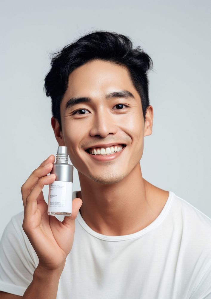 Man holding a skincare bottle portrait cosmetics smile.