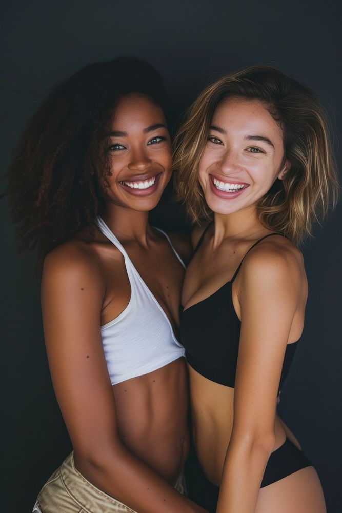 2 women body types with different ethnicities smile laughing portrait.