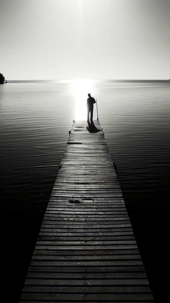 Man fishing at the dock silhouette monochrome boardwalk.