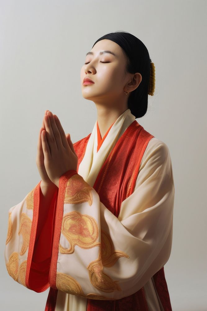 A Chinese woman wearing traditional attire is praying adult spirituality architecture. AI generated Image by rawpixel.