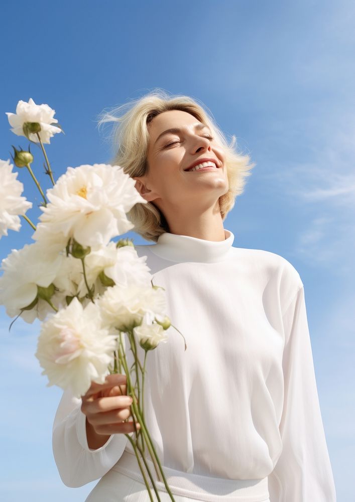Happy Mature woman wearing white outfit flower portrait outdoors.