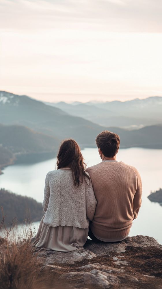 A couple sitting cutely on a mountain with lake background outdoors nature adult.