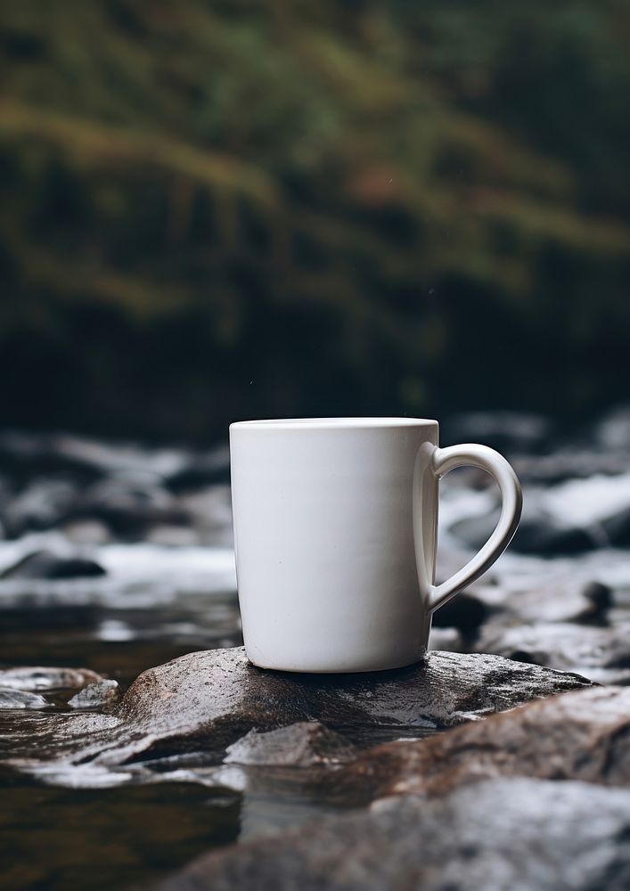 Mug on rocks with stream of water coffee drink cup.