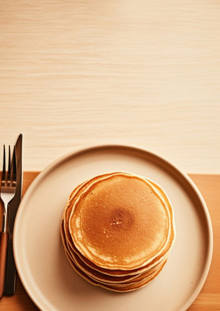 A plate with a fork and a pancakes on a table food refreshment breakfast.