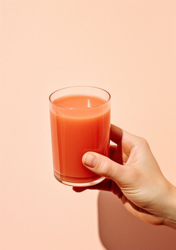 A person holding a glass of tomato juice with a tomato drink red refreshment.