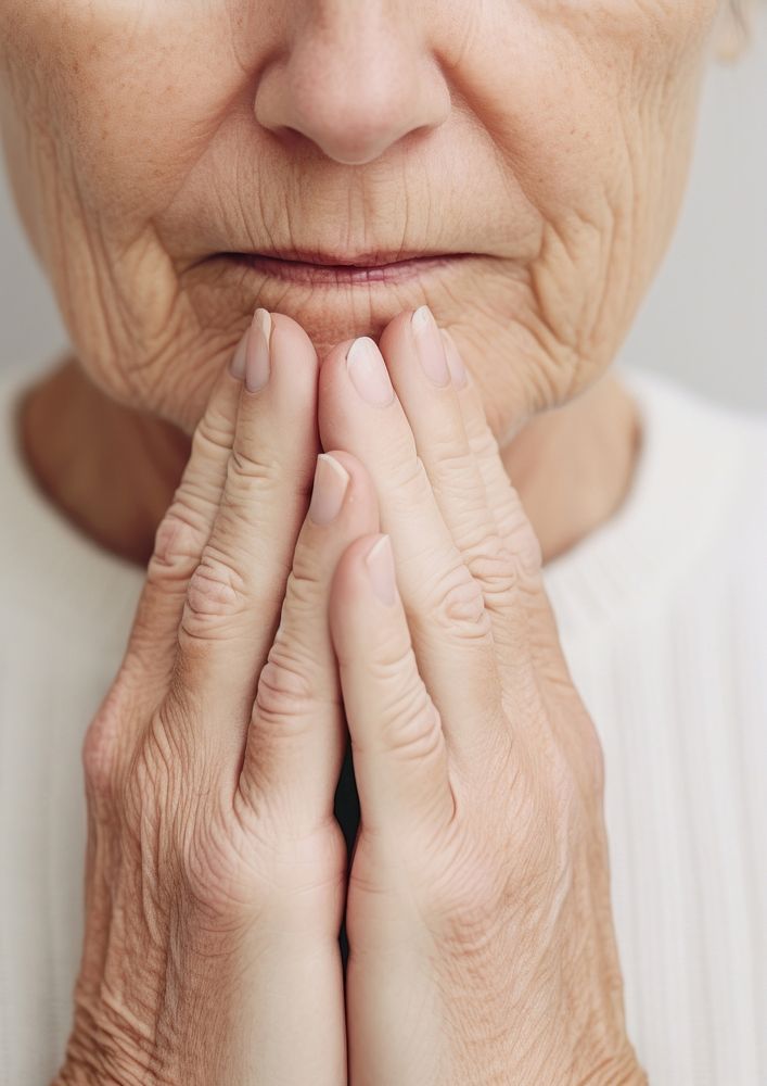 A elderly woman hand on face pain skin distraught.