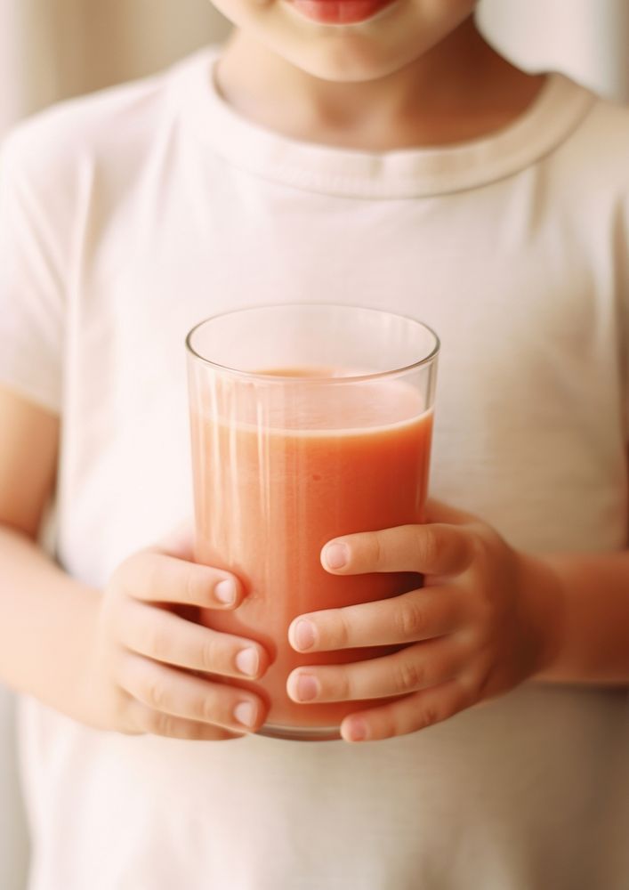 A person holding a glass of tomato juice with a tomato drink refreshment midsection.