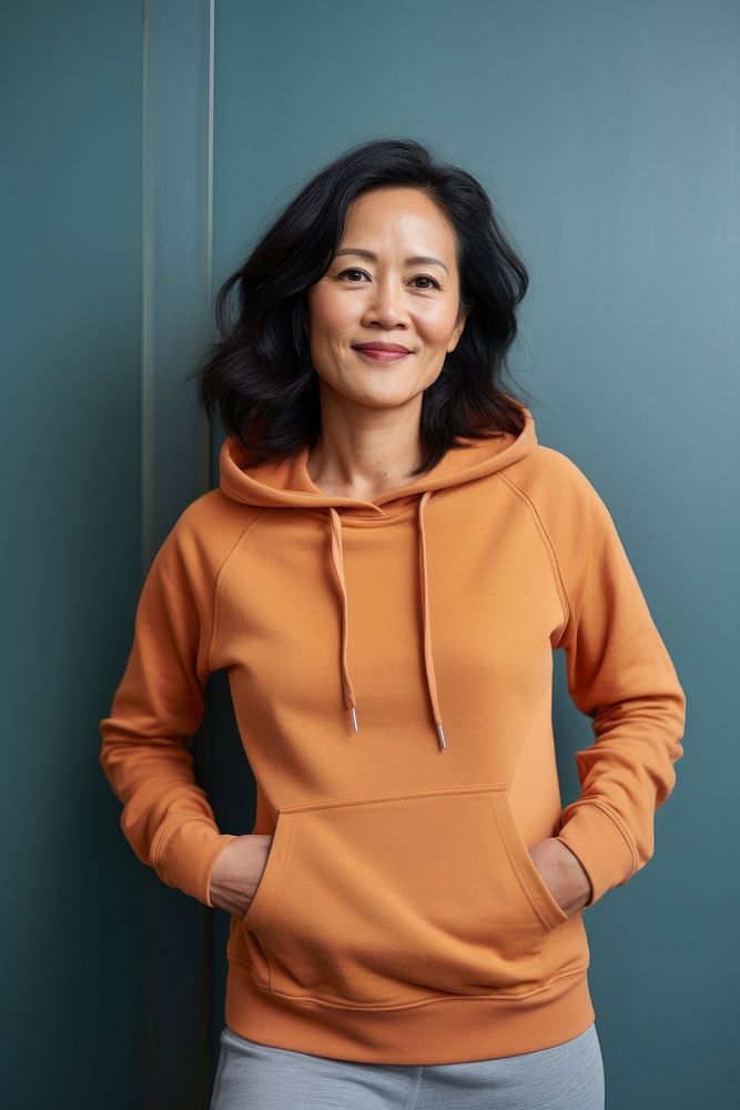 Happy asian american middle age woman wearing plain color hoodie architecture sweatshirt sweater.