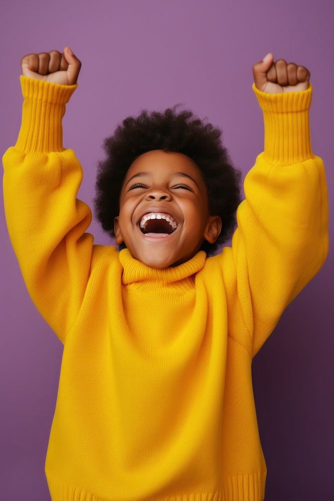 African boy with his hands up laughing sweater yellow.