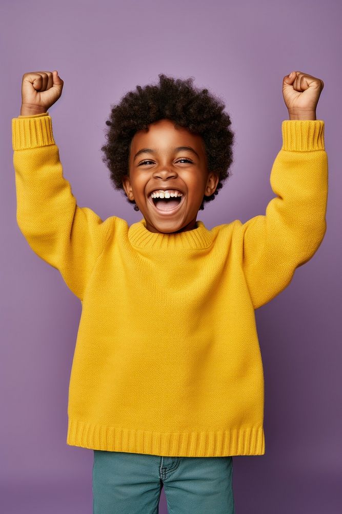 African boy with his hands up sweater laughing yellow.