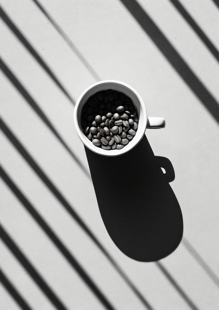 A cup of coffee beans on the table shadow black mug.