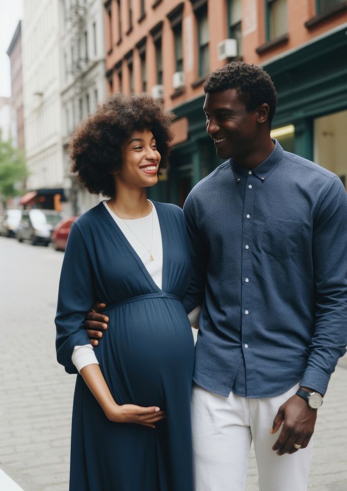 Black man holding hand pregnant woman portrait family street.