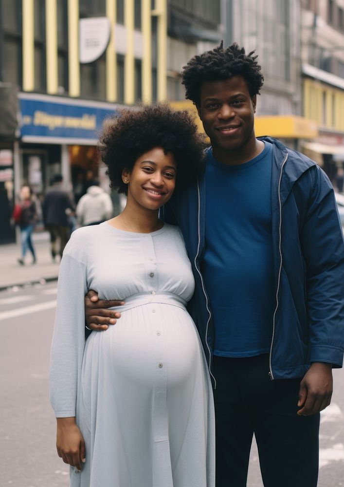 Black man holding hand pregnant black woman street portrait family.