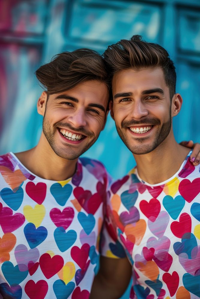 Couple gay man wearing heart-shaped matching shirts laughing smiling smile.
