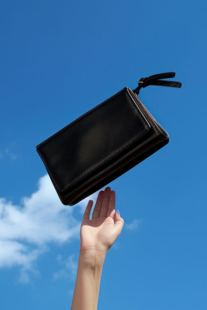 A person throwing small purse handbag wallet blue.
