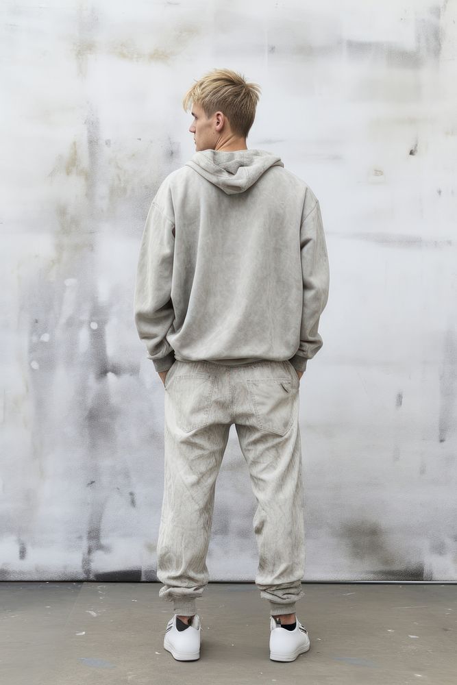 A man in jeans looking up on a white background isolation back view sweatshirt footwear standing.