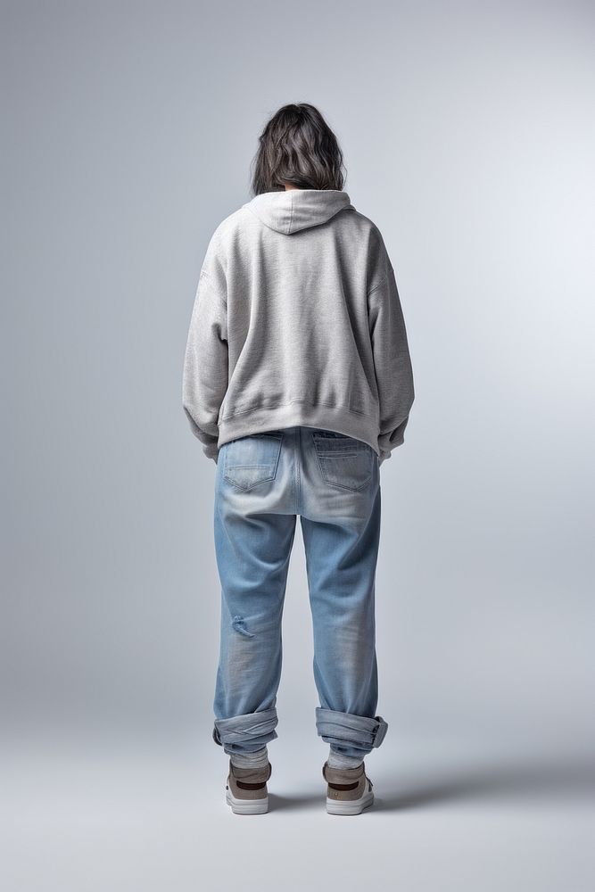 A old woman in jeans looking up on a white background isolation back view sweatshirt footwear standing.