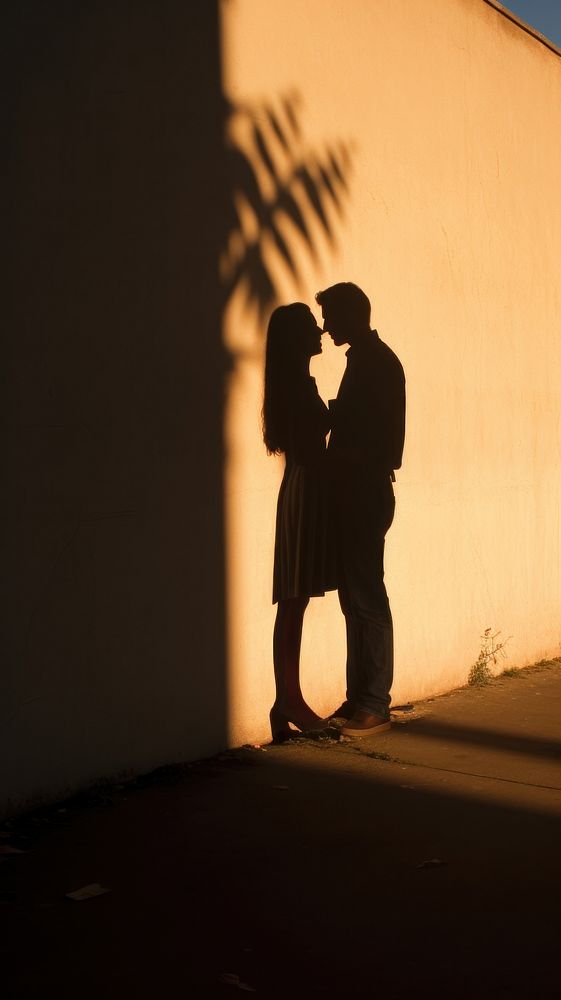 Heart-shaped shadow cast by a couple kissing against a sunlit wall sunlight romantic adult. AI generated Image by rawpixel.