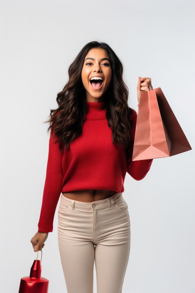 Happy young Latin lady holding shopping bags and a megaphone laughing red white background.