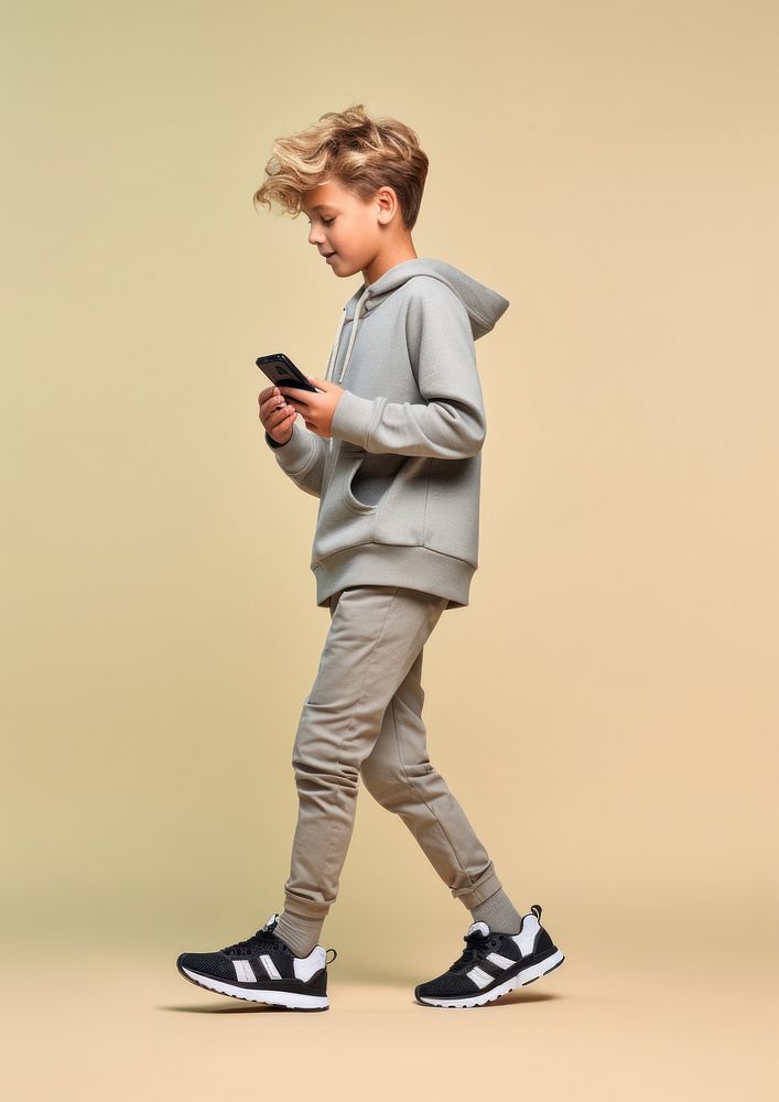 A 8 years old boy with mobile phone footwear standing person. AI generated Image by rawpixel.