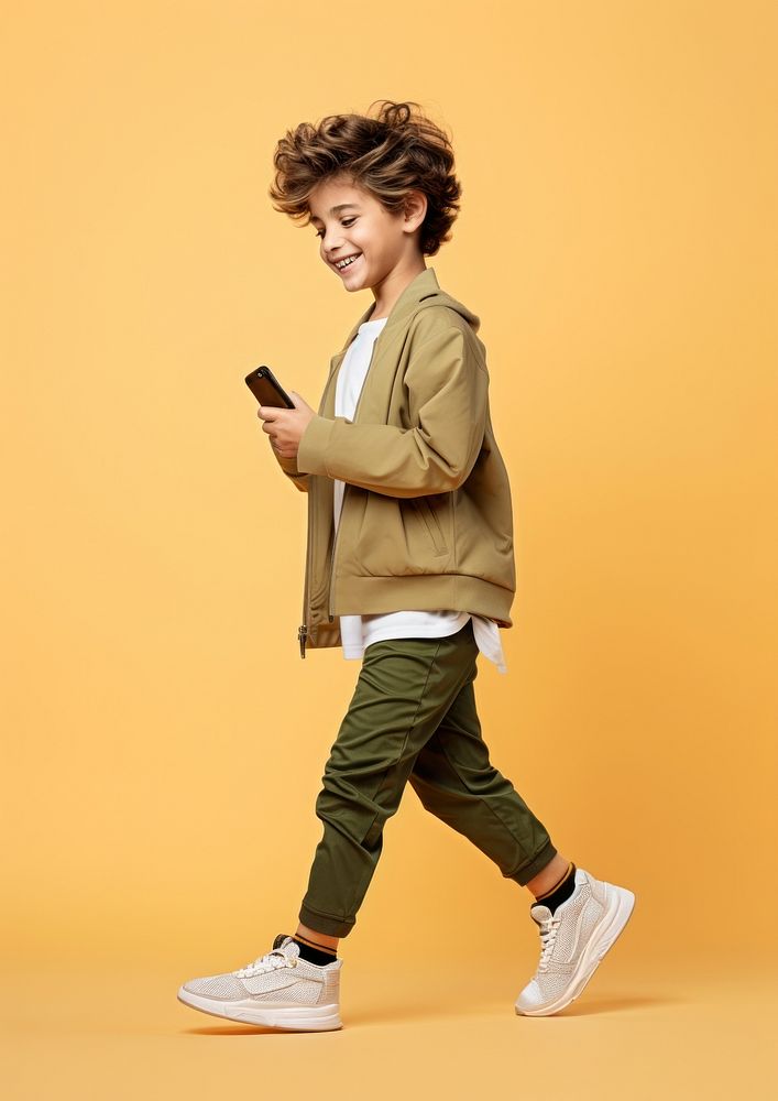 A 8 years old boy with mobile phone footwear person child. AI generated Image by rawpixel.