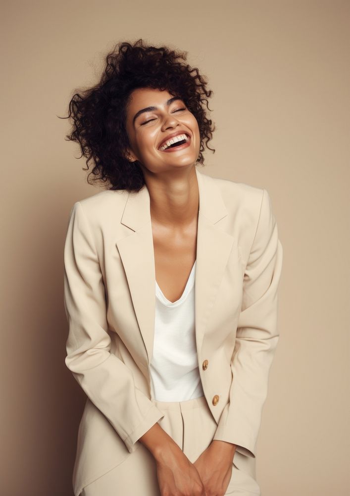 A happy mixed race british woman wear cream casual suit laughing fashion smile.