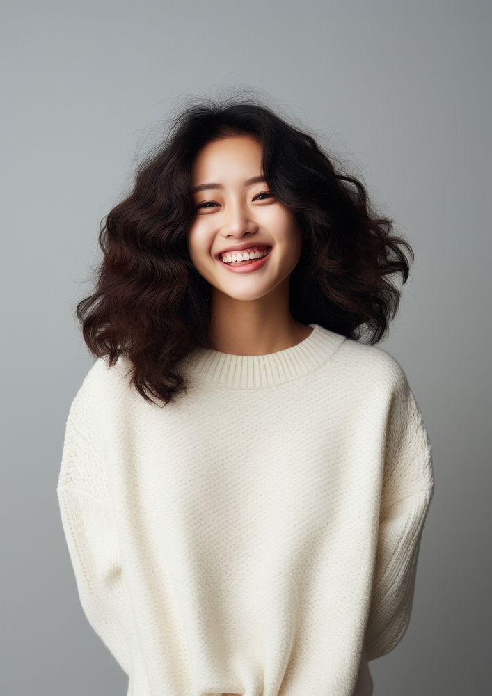 A happy mixed race korean woman wear cream sweater laughing fashion smile.