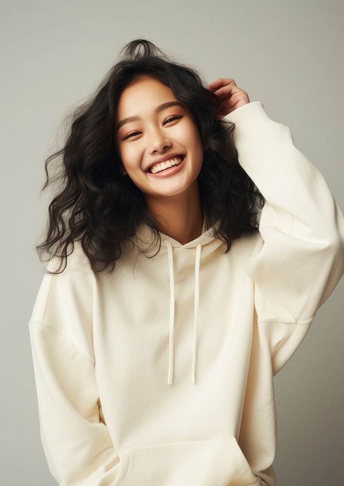 A happy mixed race korean woman wear cream hoodie laughing fashion smile.