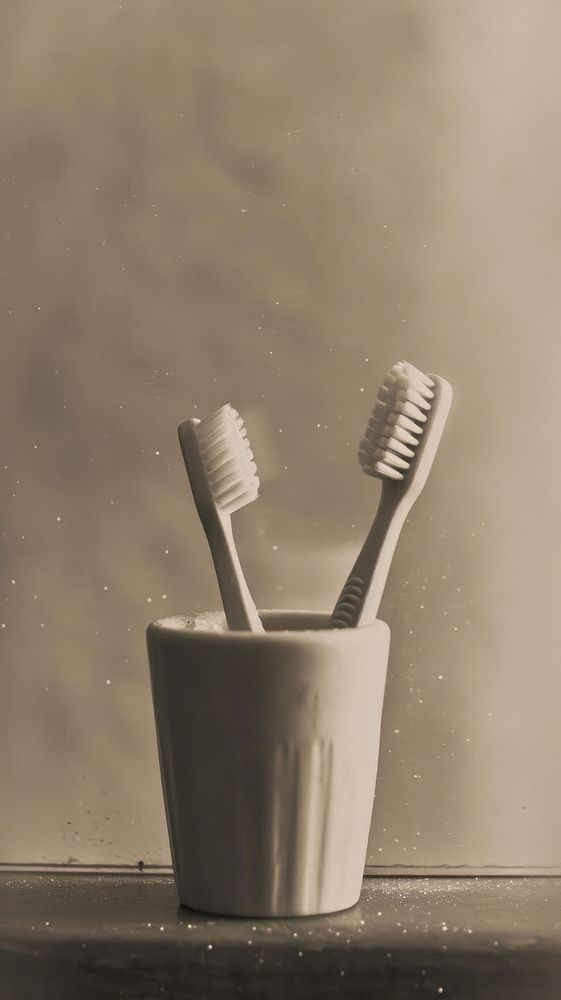 Two toothbrushes in a cup lighting hygiene device.