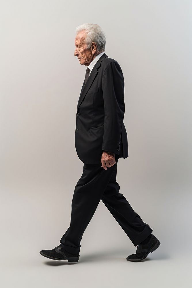 A senior man walking in studio wearing suit portrait standing tuxedo.