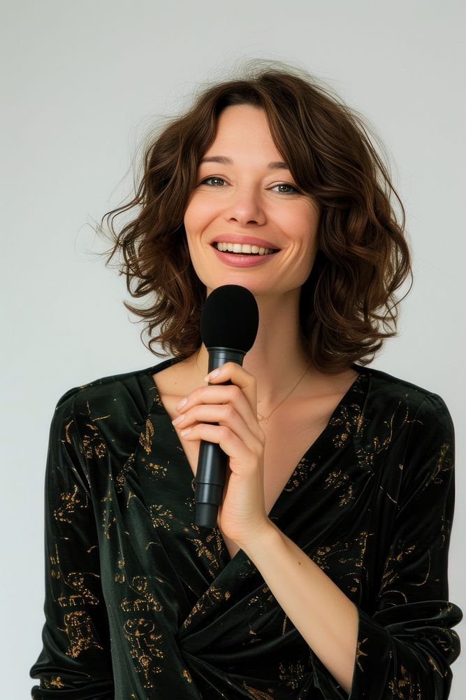A woman lecturer holding a microphone at chest level portrait smiling adult.