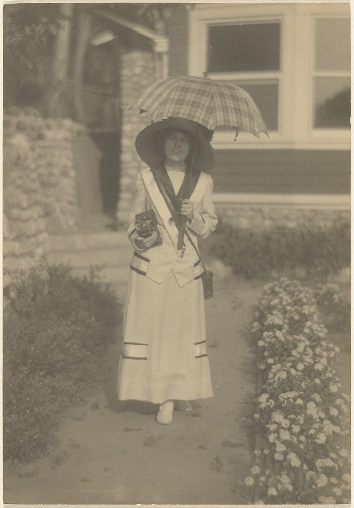 Woman Standing in Front Yard withCamera and Plaid Umbrella by Louis Fleckenstein