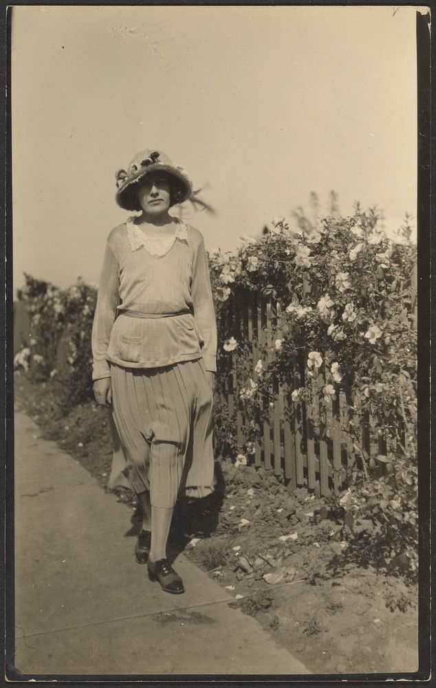 Woman Walking Along Fence with Flowers by Louis Fleckenstein