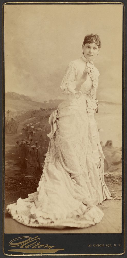 Unidentified woman wearing a long, elegant white gown, standing by Napoleon Sarony