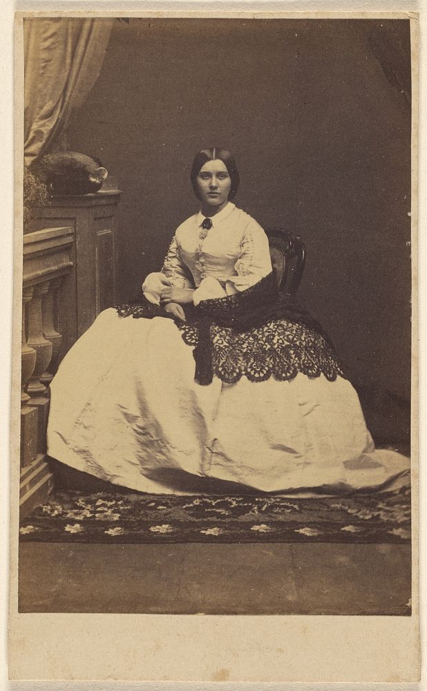 Unidentified woman in a white dress with dark shawl, seated
