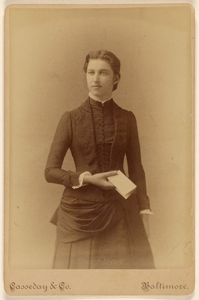 Unidentified young woman holding a piece of folded paper, standing by Casseday and Company