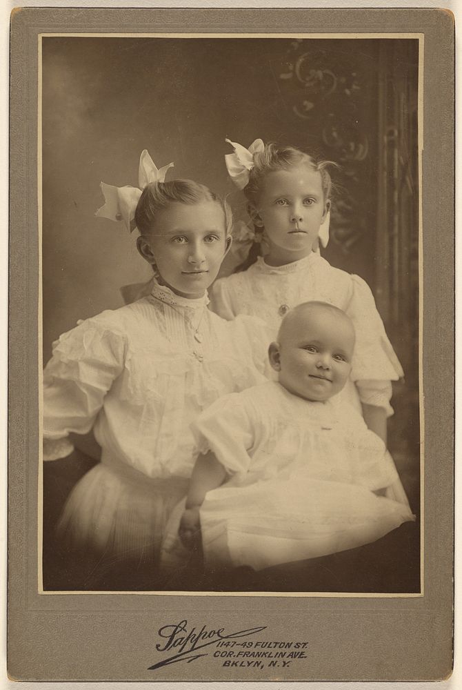 Three children: two girls standing, baby in foreground by Sappoe