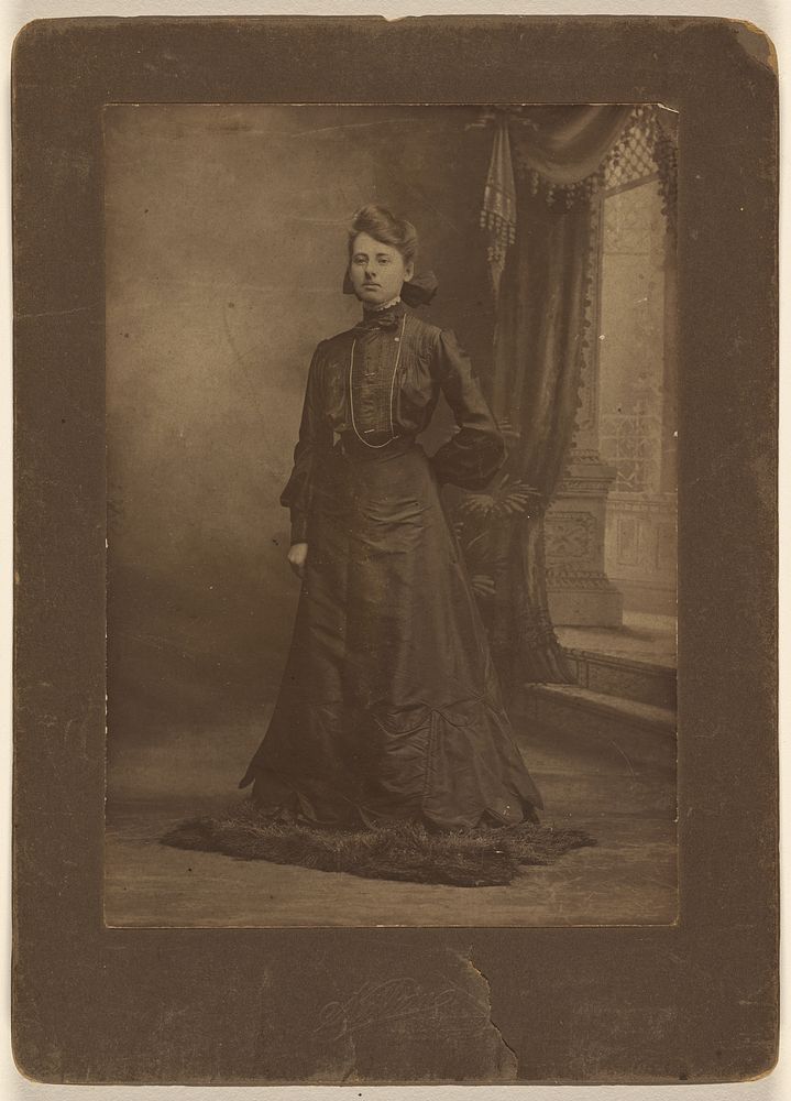 Portrait of a young woman in long black dress, standing by George W Killian