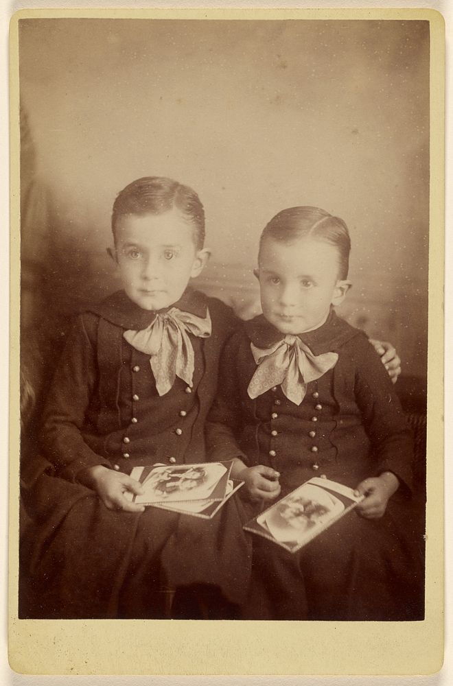 Two boys seated, holding some cabinet cards