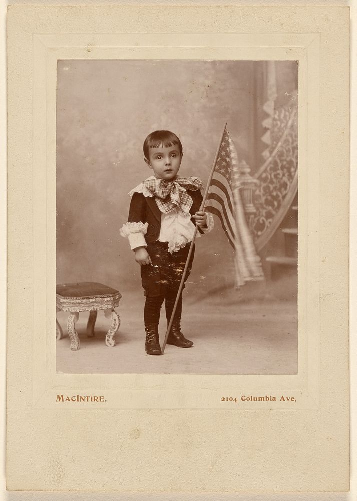 Little boy standing, holding an American flag by MacIntire