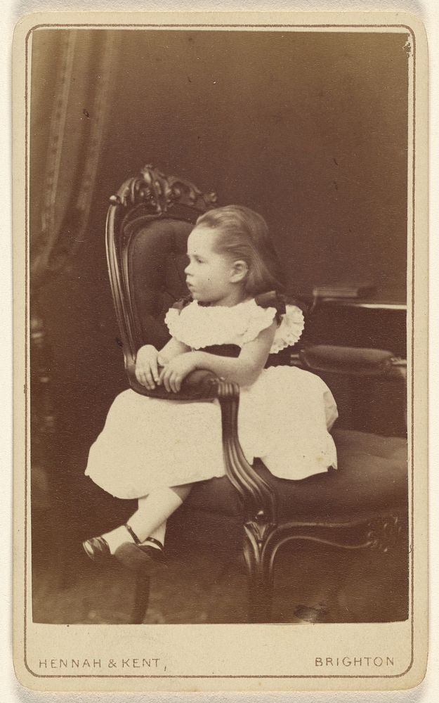 Little girl seated sideways in an armchair by Hennah and Kent